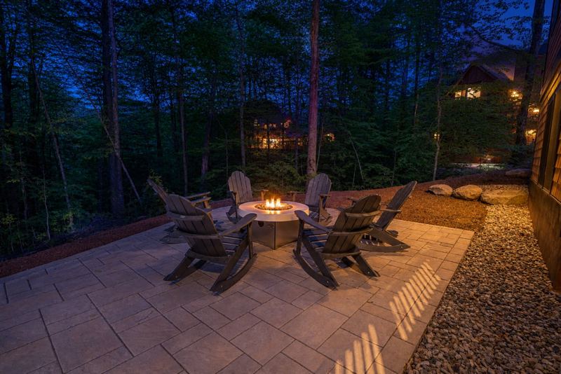 Gas fire pit ringed by Adirondack chairs